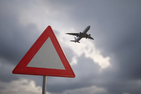 An air traffic cutback sign is displayed prominently with an airplane flying above. This scene takes place near an airport under cloudy skies. Signs indicate changes in air travel protocols.の素材