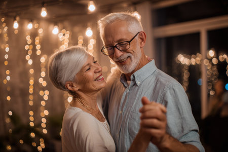 A joyful elderly couple dances closely in a warm, cozy room. Soft fairy lights create a romantic atmosphere as they share smiles and laughter, making lasting memories together.の素材