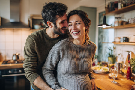 A couple smiles and laughs in a kitchen as they discuss plans for their new baby. The room is welcoming and filled with items for family life. They share a moment of joy together.の素材