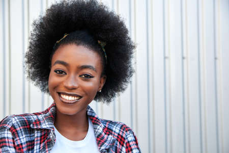 Positive emotions and people concept â happy african american woman with curly hair over grey background, copy space. Lifestyle in city.の写真素材