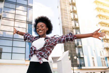 Positive emotions and people concept young black african american female with curly black hair. Over city background. Lifestyle.の写真素材