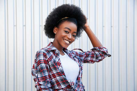 Positive emotions and people concept young black african american female with curly black hair. Over city background. Lifestyle.の写真素材