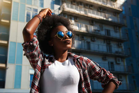 Positive emotions and people concept young black african american female with curly black hair. Over city background. Lifestyle.の写真素材