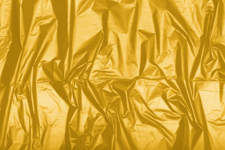 Texture of crumpled glossy textile toned in Fortuna Gold, color 2021.の写真素材