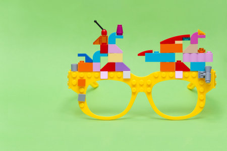 Kid's blocks building on yellow glasses on green background. Educational and creativity concept.の写真素材