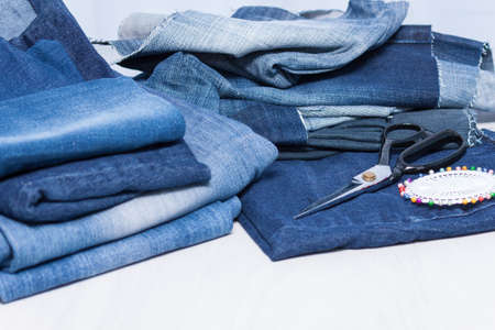 Stack of old blue jeans for recycling on white background.の写真素材