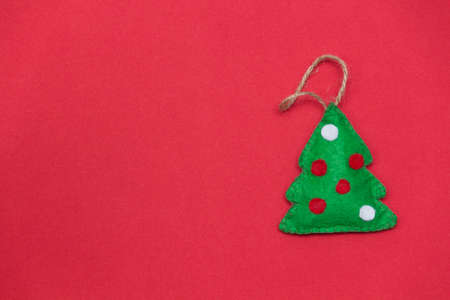 Christmas tree on red background. Handmade toy from felt. DIY concept. Copy space.の写真素材