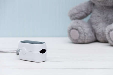 Pulse oximeter for measure pulse rate and oxygen level on white wooden table. Healthy concept.