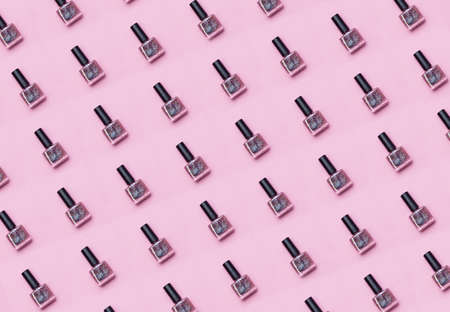 Bottles of nail polish with sequins and glitter on pink background. Beauty and fashion concept. Flat...