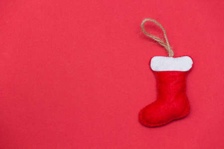 Red christmas sock on red background. Handmade toy from felt. DIY concept. Copy space.の写真素材