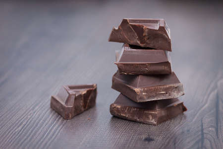 Pieces of dark chocolate on brown wooden background. Copy space.の写真素材