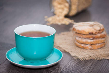 Homemade oatmeal cookies with cup of tea on wooden background. Healthy food snackの写真素材