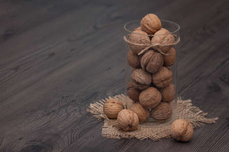 Whole walnuts in a glass jar on a rustic wooden background. Healthy food, snack. Copy space.の写真素材