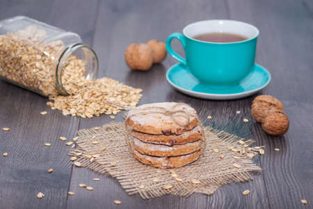 Homemade oatmeal cookies with walnut, cup of tea on wooden background. Healthy food snackの写真素材