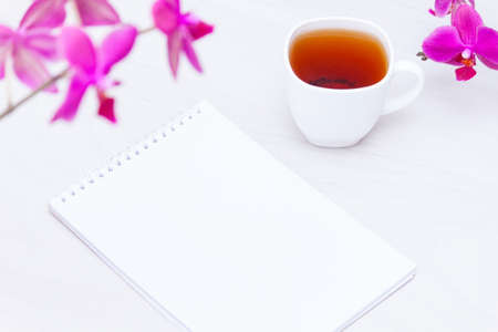 Cup of tea, flowers, paper notebook on white background. Copywriting, freelance concept.の写真素材