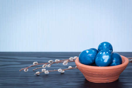 Blue space galactic Easter eggs in clay plate on wooden background. Close up. Easter greeting card. Copy space.の写真素材
