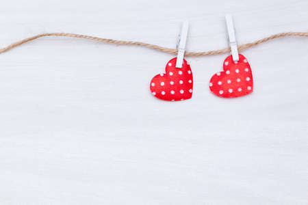 Two red hearts hanging on a thread on white wooden background. Valentine's Day, love, wedding concept. Flat lay, top view.の写真素材