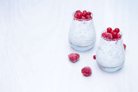 Healthy vanilla chia pudding with red berries on white wooden background. Healthy snack concept. Copy space.の写真素材