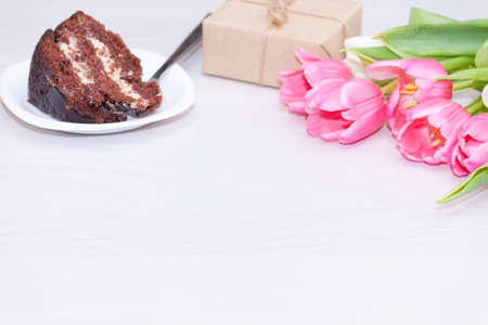 Bouquet of pink tulips, chocolate cake. pressent box on white wooden background. Copy space, close up. Mother's, women's day concept.の写真素材