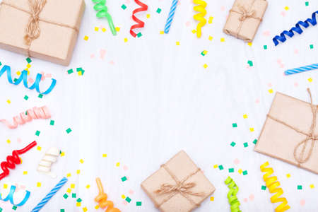 Colorful gifts, confetti, candles, streamers on white wooden background. Flat lay, copy space, holiday frame or background.の写真素材