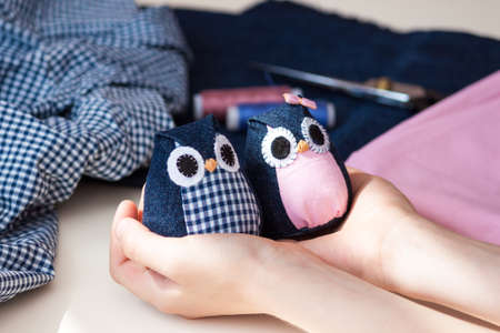 Child holds in his hands hand made owls. Craft tools and materials on the table.の写真素材