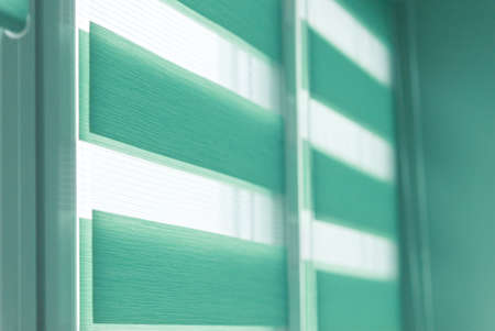 Close up of colored fabric roller blinds on window. Roll curtains.の写真素材