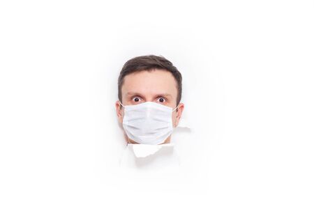 Portrait of a man on a white isolated background, face covered with a medical mask, banner for text. Health, awareness, and timeliness. Healthy lifestyle. No viruses. Fear of getting sickの写真素材