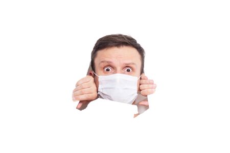 Portrait of a man on a white isolated background, face covered with a medical mask, banner for text. Health, awareness, and timeliness. Healthy lifestyle. No viruses. Fear of getting sickの写真素材