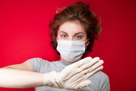 Stop the virus and epidemic diseases. Healthy woman in blue medical protective mask showing gesture stop. Health protection and prevention during flu and infectious outbreakの写真素材