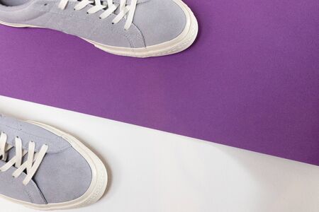 White and grey mens sneakers on a white and purple background. Flat spoon, top view minimal background. The concept of a Fashion blog or magazine.の写真素材