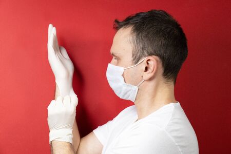 Professional medic in protective mask on face putting on blue latex gloves on hands. Young man surgeon in face mask wearing sterile medical glove. Medical examination in hospital. Coronavirus COVID-19の写真素材