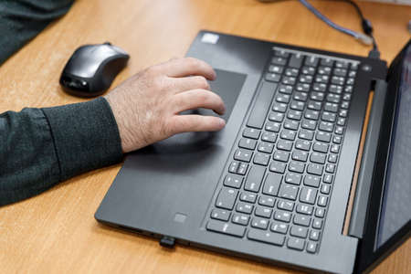 Businessman at work. Close-up top view of man working on laptop while sitting at the wooden deskの写真素材