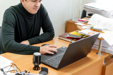 Businessman at work. Close-up top view of man working on laptop while sitting at the wooden deskの写真素材