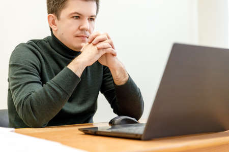Businessman at work. Close-up top view of man working on laptop while sitting at the wooden deskの写真素材