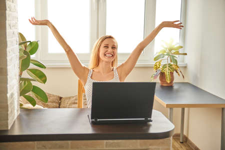 Portrait of an attractive woman on a chair at a table with a laptop, home office, remote work. Relax. The concept of work and rest. Concept photoの写真素材
