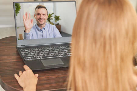 Focus on the screen with a happy middle-aged man making a video call with his colleague, chatting online using a computer app while staying at home in quarantine.の写真素材