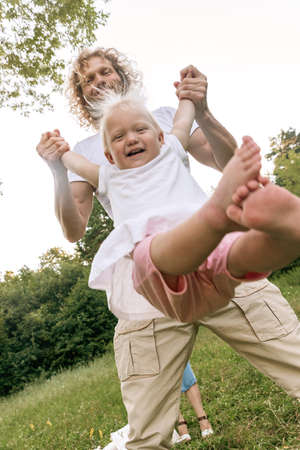 Father and daughter playing on the grass at the day time. Concept of friendly family.の写真素材