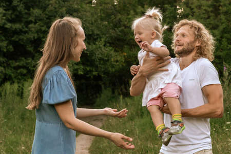 Happy family in the Park at sunset. Summer picnic. The concept of a healthy family. Mom, dad, daughter. Weekend in nature.の写真素材