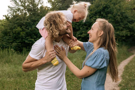 Happy family in the Park at sunset. Summer picnic. The concept of a healthy family. Mom, dad, daughter. Weekend in nature.の写真素材
