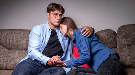 A sad couple is sitting on the sofa at home, copying the space. Quarrel, relationship. Upset girlの写真素材