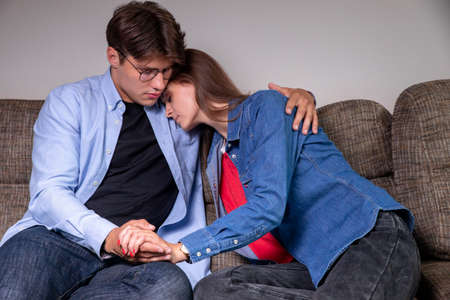 A sad couple is sitting on the sofa at home, copying the space. Quarrel, relationship. Upset girlの写真素材
