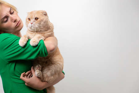 Studio portrait of an attractive woman with braces holding a cat in her hands, isolated on a white backgroundの写真素材