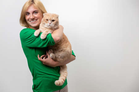 Studio portrait of an attractive woman with braces holding a cat in her hands, isolated on a white backgroundの写真素材