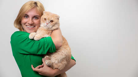 Studio portrait of an attractive woman with braces holding a cat in her hands, isolated on a white backgroundの写真素材