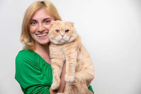 Studio portrait of an attractive woman with braces holding a cat in her hands, isolated on a white backgroundの写真素材