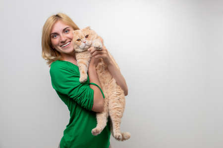 Studio portrait of an attractive woman with braces holding a cat in her hands, isolated on a white backgroundの写真素材