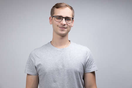 Close-up portrait of a smiling business man with glasses looking at the camera with a smile isolated on a white-gray backgroundの写真素材