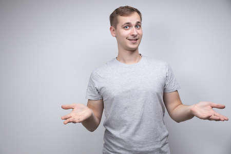 Studio portrait concept of a smiling young man talking on a white background. He stands directly in front of the camera in different poses with different emotions.の写真素材