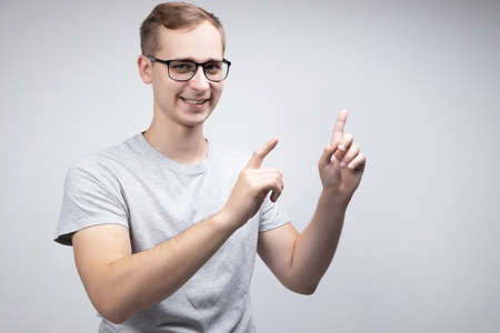 A happy male actively gestures, expresses positive emotions after receiving a salary or bonus, and enjoys his success isolated above a white concrete wall. The concept of people, happiness, and body languageの写真素材