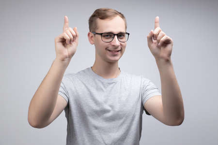 A happy male actively gestures, expresses positive emotions after receiving a salary or bonus, and enjoys his success isolated above a white concrete wall. The concept of people, happiness, and body languageの写真素材